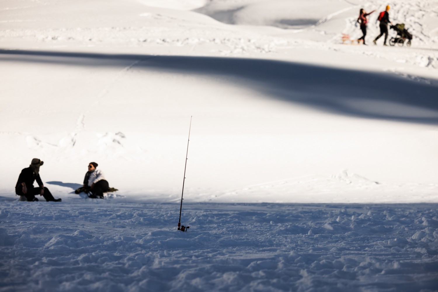 Dann wird gewartet. Auch Eisfischer schätzen zwischendurch die Sonne. Bild: Severin Nowacki