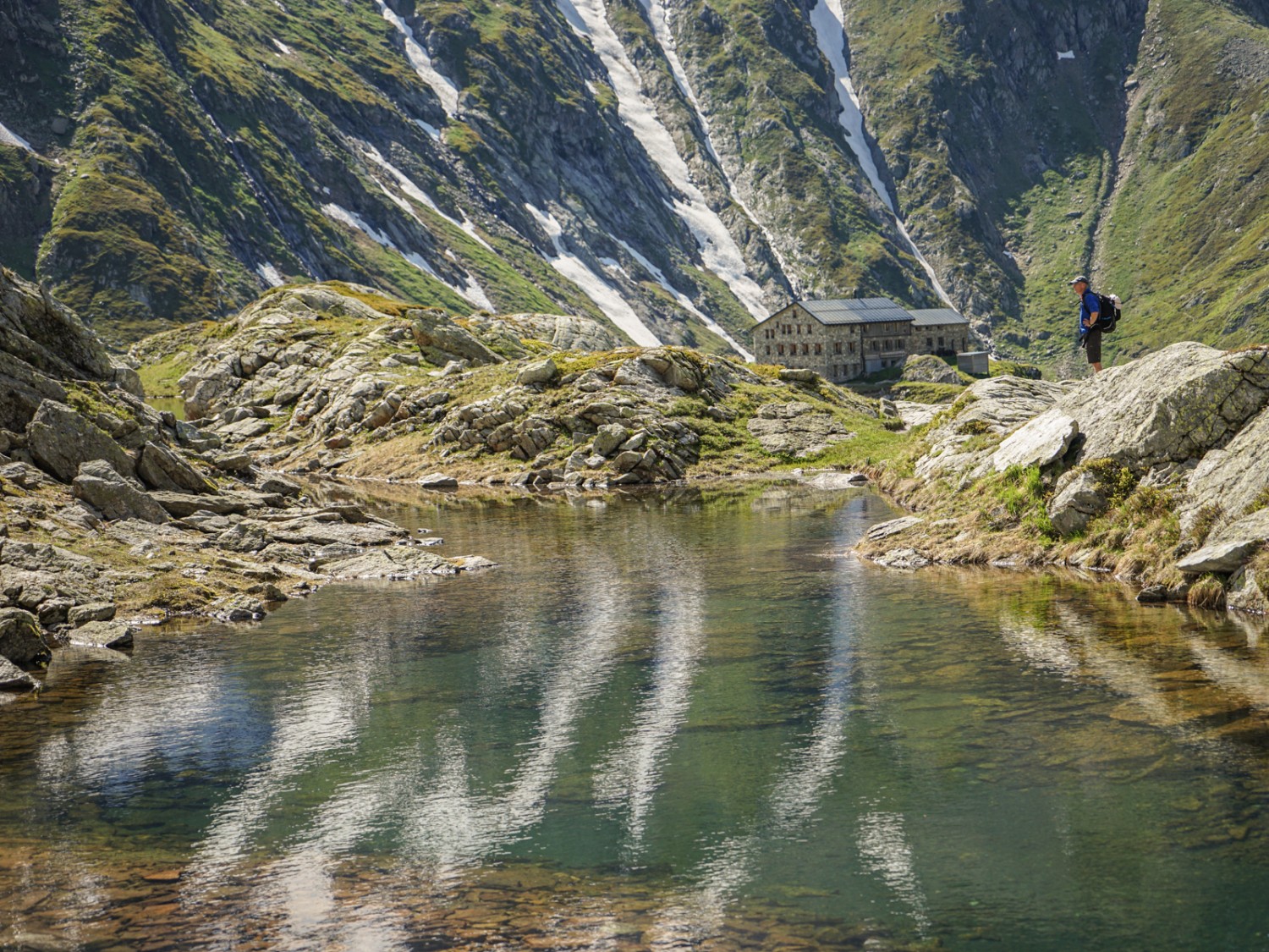 Gli ultimi nevai si riflettono nel laghetto senza nome al di sopra del rifugio Camona da Terri. Foto: Reto Wissmann