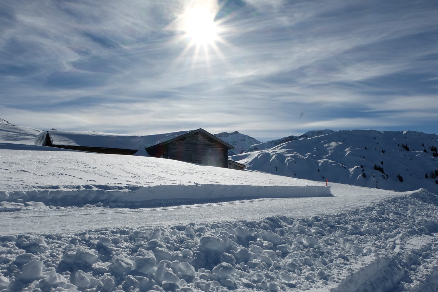 Tief verschneit sind die Alphütten im Winter. Langläufer und Winterwanderer ziehen vorbei.